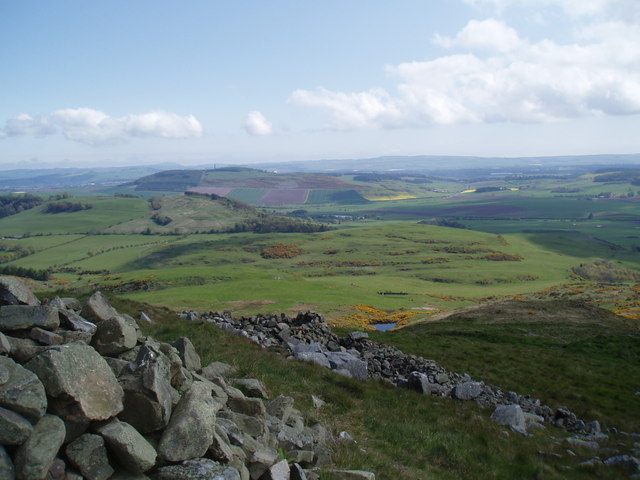 Ploughed fields and woodland falling away to the Firth of Tay, seen from the grassy ramparts of Norman's Law